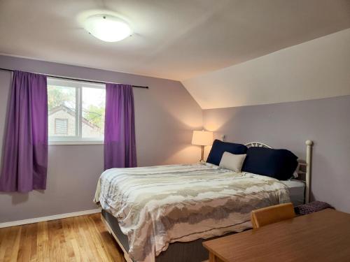 1 dormitorio con 1 cama y una ventana con cortinas moradas en Winnipeg Place to Stay, en Winnipeg