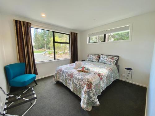 ein Schlafzimmer mit einem Bett, einem Stuhl und einem Fenster in der Unterkunft Alpine Views and River Tracks in Twizel