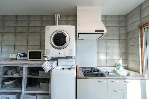 a kitchen with a washer and a white refrigerator at ユナパ in Yonaha