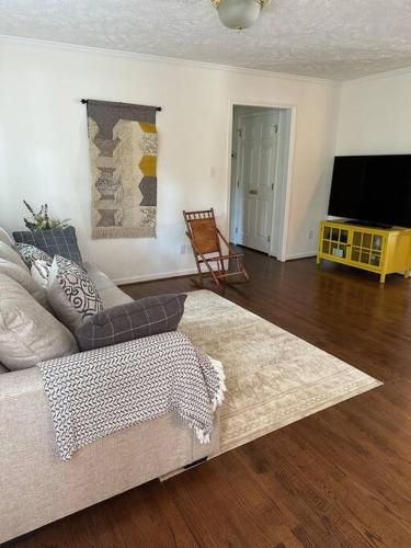 a living room with a couch and a flat screen tv at The Mirror Lake Suite in Fayetteville