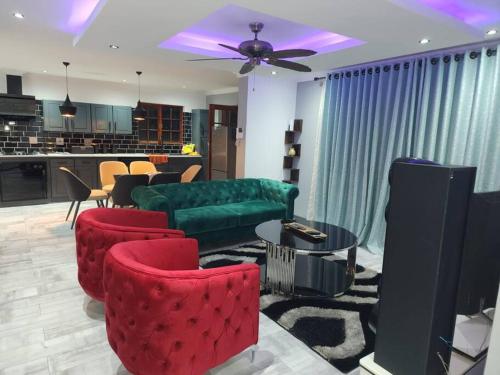 a living room with a green couch and red chairs at Jo's Eden in Edenvale