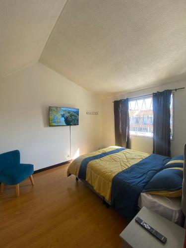 um quarto com uma cama, uma cadeira e uma janela em Hostel Urban City Bogotá em Bogotá