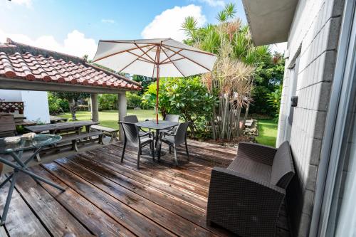 a wooden deck with a table and an umbrella at ユナパ in Yonaha