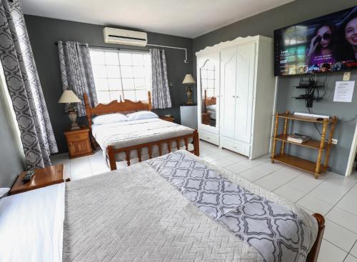 a bedroom with two beds and a flat screen tv at Airport Inn in Piarco