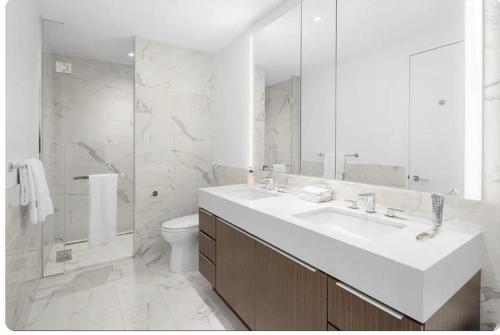 a white bathroom with a sink and a toilet at Stunning views of Manhattan in New York