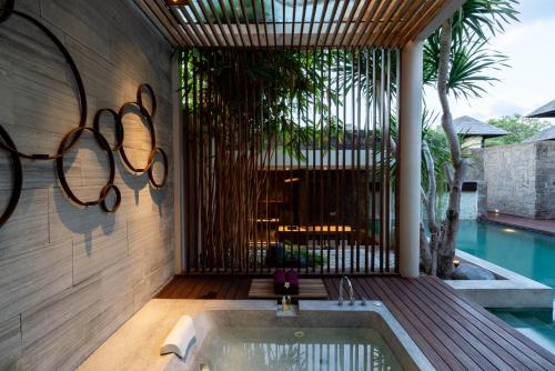 a bathroom with a bath tub next to a swimming pool at Berry Amour Romantic Villas in Seminyak