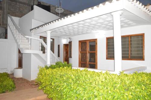 a white house with a staircase and bushes at Gloryphil House in Lomé