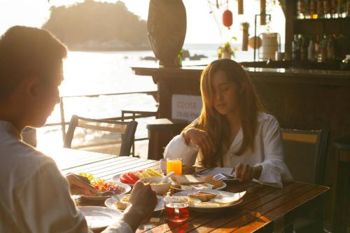 Ein Mann und eine Frau sitzen am Tisch und essen Essen. in der Unterkunft Anda Lipe Resort in Ko Lipe