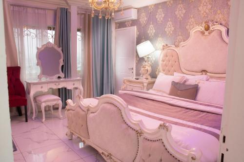 Habitación de color rosa con cama grande y lámpara de araña. en Rovie Estates, en Buea