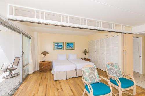 a bedroom with a white bed and two chairs at Ilikai Tower 618 Lagoon View 1BR in Honolulu