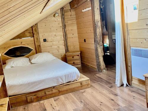 a bed in a room with wooden walls and wood floors at Chalet 4 pièces avec balcon, BBQ, parking, WIFI à Châtel - FR-1-676-43 in Châtel