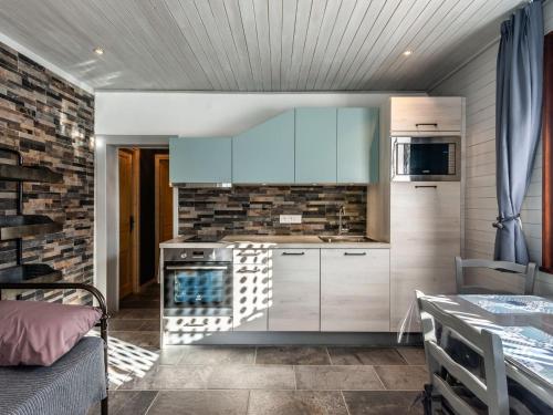 une cuisine avec des placards blancs et un mur en briques dans l'établissement Châlet cosy à Châtel: Terrasse, 2 pièces pour 3 pers., proche centre et remontées mécaniques - FR-1-676-2, à Châtel