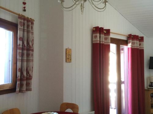 une salle à manger avec des rideaux rouges et une table dans l'établissement Charmant Duplex avec Mezzanine - Balcon Exposé Sud et Proche Télésiège - 5 Personnes - FR-1-676-53, à Châtel