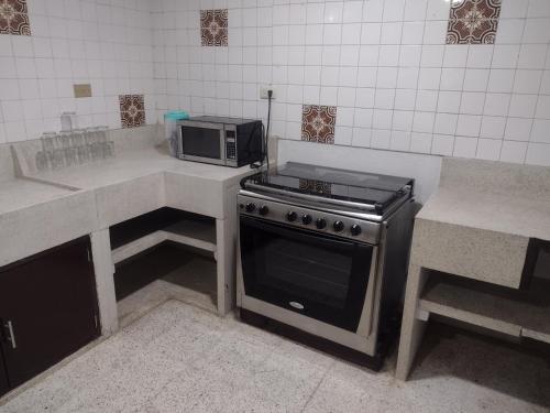 eine Küche mit einem Herd und einer Mikrowelle in der Unterkunft Amplia Casa centro de Teziutlán in Teziutlán
