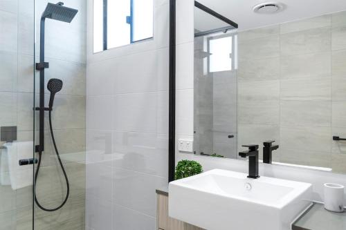 uma casa de banho branca com um lavatório e um chuveiro em Mountain Air and Modern Flair 'Your Cairns Getaway' em Cairns