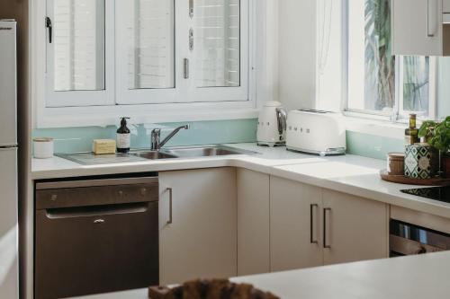 a kitchen with white cabinets and a sink at The Beach House, 25 Tomaree Road - fantastic house with pool, linen in Shoal Bay