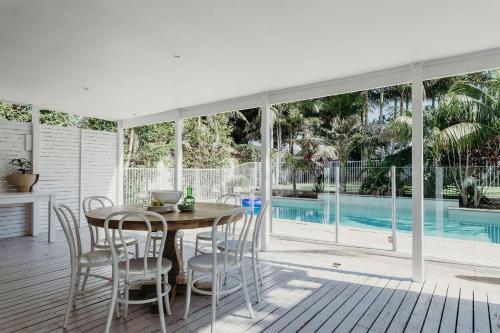 a dining room with a table and chairs and a pool at The Beach House, 25 Tomaree Road - fantastic house with pool, linen in Shoal Bay