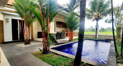 a house with a swimming pool with palm trees at Rama Bharata Villa in Ubud