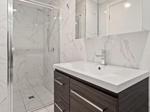 a white bathroom with a sink and a shower at Snoqualmie 3 2 Cobbodah St in Jindabyne