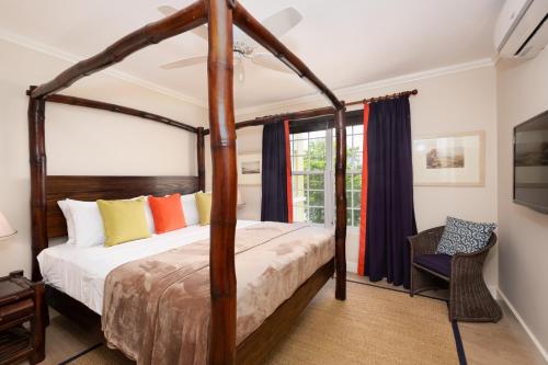 a bedroom with a canopy bed and a chair at Jamaica Time Driftwood at Sea Palms 3BR 3BA Condo in Ocho Rios with Pool and Beach Front with Views ONLY 10 Mins from Ochi Intl Airport Direct flight from Miami in St Mary