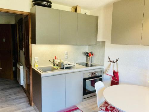- une cuisine avec des placards blancs, un évier et une table dans l'établissement Appartement cosy 2 pièces, 4 pers, Châtel – Balcon, parking, proche télécabine et centre - FR-1-676-123, à Châtel