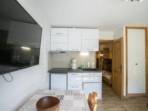 une petite cuisine avec des armoires blanches et une table dans l'établissement Appartement cosy à Châtel, 100m des pistes, balcon, WiFi, parking, jusqu'à 4 personnes - FR-1-676-105, à Châtel