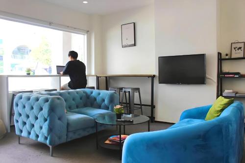 un hombre de pie en una sala de estar con dos sofás azules en Beary Best! Hostel Chinatown en Singapur
