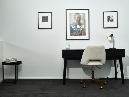 a desk with a chair and a poster on a wall at Chic Urban Loft in Prime Location in Melbourne