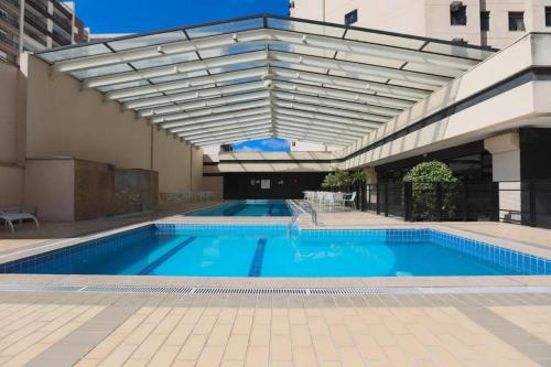 una grande piscina con tenda da sole accanto a un edificio di Suite Congonhas - FLAT Aeroporto Congonhas a San Paolo
