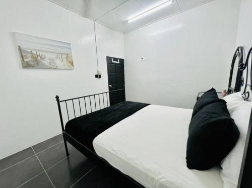 a bedroom with a bed with white sheets and black pillows at Homestay CikPuteh Gunong, Bachok in Bachok