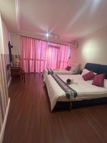 a bedroom with two beds and a pink window at Riverbank suites unit 405 in Kuching
