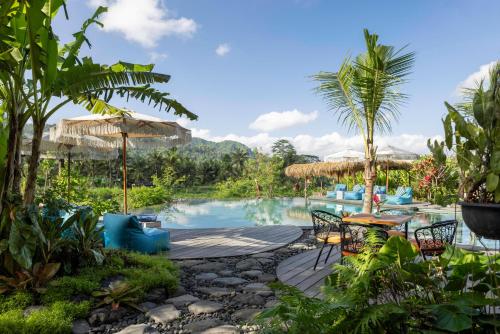um resort com piscina, mesas e cadeiras em Natya River Sidemen em Silebeng
