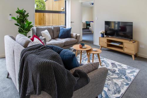 a living room with a couch and a tv at 3 Bed 2.5 Bath Riccarton W/Games room in Christchurch