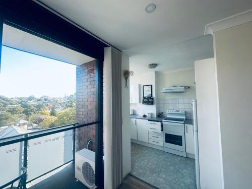 une cuisine avec des placards blancs et une grande fenêtre dans l'établissement Wandering a private room with shared bathroom, à Sydney