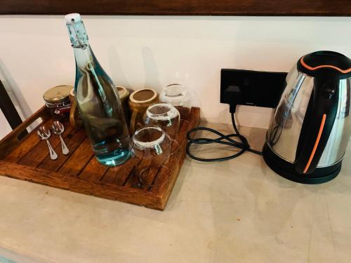 a bottle and glasses on a wooden tray with a blender at Mango Tree House in Udawalawe