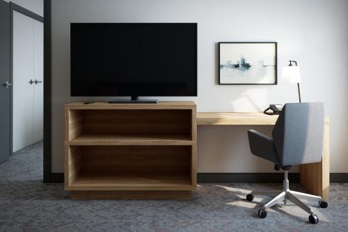 a tv on a desk with a chair and a computer at Candlewood Suites - Layton - Salt Lake City by IHG in Layton