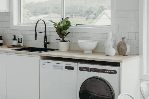 een keuken met een wasmachine en een wastafel bij Baybreeze 18 Tomaree Road WiFi Air Conditioning Kitchenette in Shoal Bay