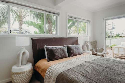 een slaapkamer met een bed en 2 ramen bij Baybreeze 18 Tomaree Road WiFi Air Conditioning Kitchenette in Shoal Bay