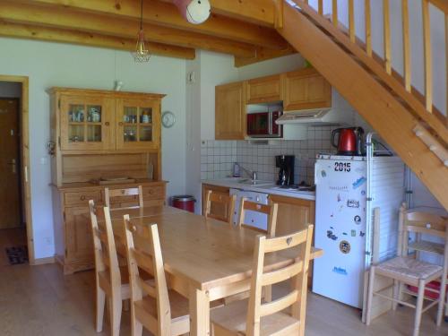 une cuisine avec une table en bois et un réfrigérateur blanc dans l'établissement Duplex confortable avec balcon sud, animaux admis et parking - FR-1-629-133, à Samoëns