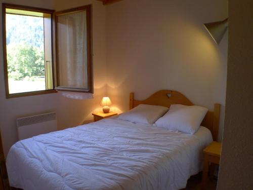 une chambre avec un lit blanc avec une fenêtre dans l'établissement Duplex confortable avec balcon sud, animaux admis et parking - FR-1-629-133, à Samoëns