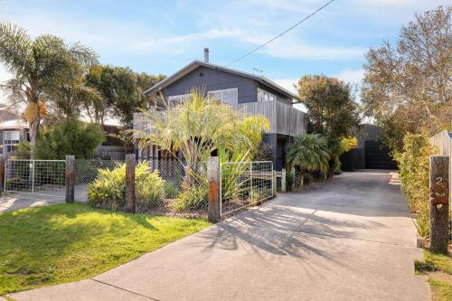 a house with a fence next to a driveway at Seaspray Getaway in Cape Woolamai