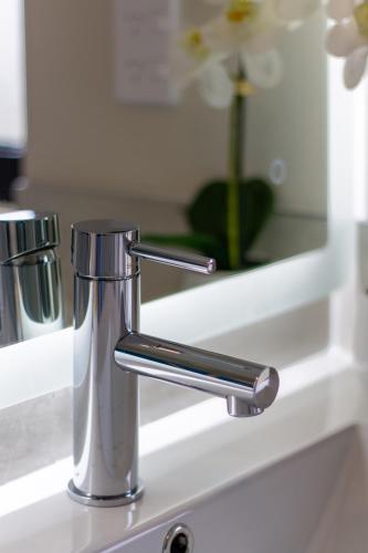 a chrome bathroom sink faucet in front of a mirror at 3 Bed 2.5 Bath Riccarton W/Games room in Christchurch