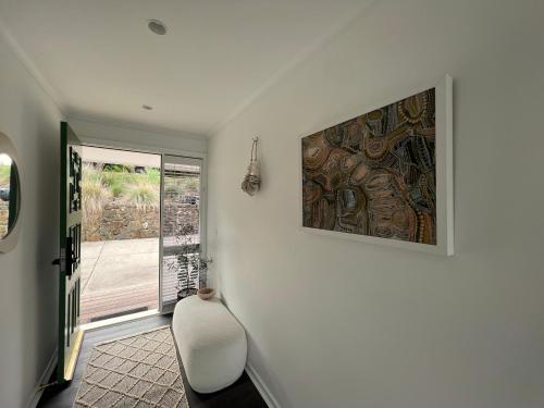 a room with a white chair and a painting on the wall at Rye Beach House - Sunset Views in Rye