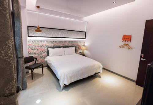a bedroom with a white bed and a brick wall at Travel Mind in Hualien City