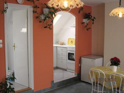 a kitchen with orange walls and a table and a dining room at Fured Apartments in Balatonfüred