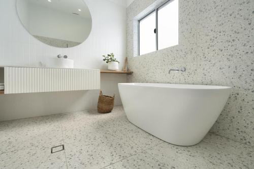 a white bathroom with a tub and a mirror at Boat Harbour Haven in Bonnells Bay