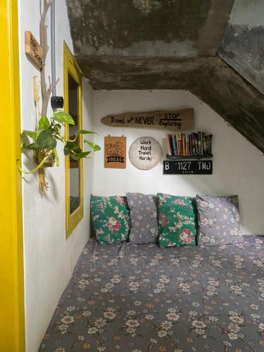 Cette chambre comprend un lit avec des oreillers et une étagère à livres. dans l'établissement Banana Homestay, à Banyuwangi