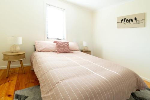 a bedroom with a bed with a pink comforter and a window at Sunset Meadows in Sunset Strip