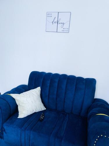 a blue couch with a white pillow on it at One bed airbnb with pool by Omuts in Kiambu