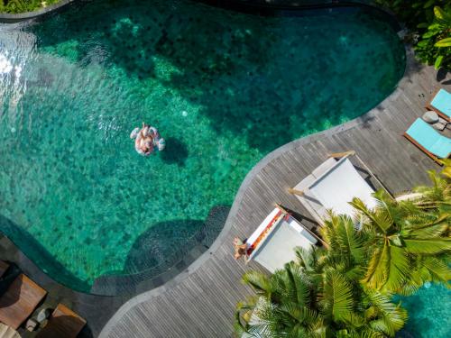 an overhead view of a pool with people in the water at Aksari Resort Ubud by Ini Vie Hospitality in Tegalalang